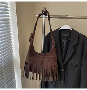 Detail van een bruine suède tas met lange franjes en een geknoopte schouderriem boho