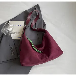 Détail d'un sac cabas en daim bordeaux avec cordon de zip vert et bandoulière en cuir