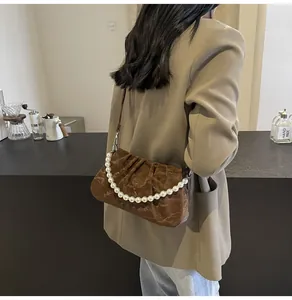 Detail of coffee brown pleated shoulder bag with elegant pearl strap and leather strap