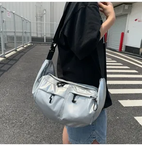 Detail view of large silver nylon crossbody bag with dual drawstring pockets and strap