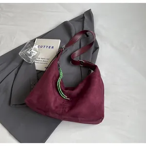 Détail du sac hobo en daim bordeaux avec breloque en corde tressée et boucle argentée