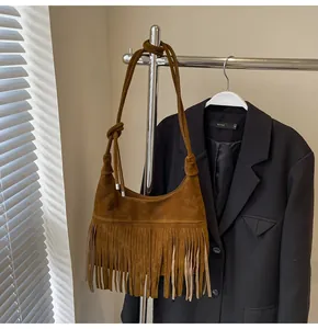 Detailopname van bruine suède crossbodytas met lange franjes en een geknoopte schouderriem