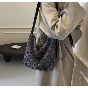 Gros plan d'un sac cabas léopard avec bandoulière noire porté par un mannequin