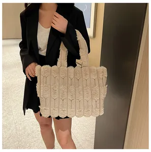 Close-up of a large beige plush tote bag with V-shaped textured patterns on a model