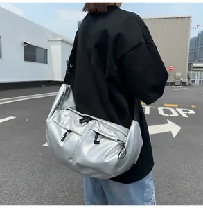 Detail of silver metallic nylon crossbody bag featuring double front zipper pockets and wide strap