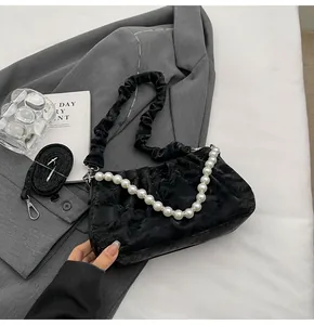 Detail of black pleated cloud bag with pearl chain and adjustable strap on a suit