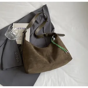 Gros plan détaillé d'un sac hobo en daim marron avec coutures et breloque tissée