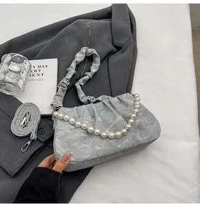 Detail of light grey pleated cloud bag with pearl chain and adjustable shoulder straps