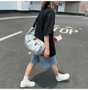 Outdoor shot of a shiny silver crossbody bag with adjustable black straps and buckle