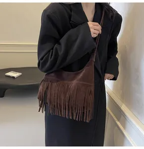 Detail van donkerbruine suède crossbodytas met lange franjes en retro minimalistische riem