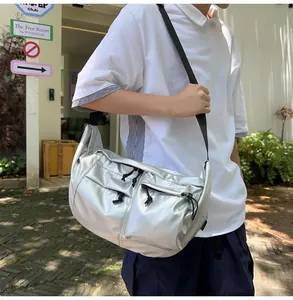Detail of silver metallic crossbody bag featuring front zipper pockets and nylon strap