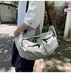 Detail of silver metallic nylon crossbody bag with multiple front zipper pockets