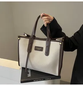 Detalle de bolso tote de lona con ribete de cuero marrón y etiqueta de moda frontal