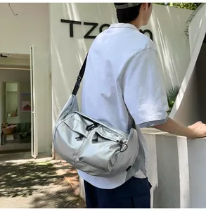 Outdoor shot showing silver techwear crossbody bag with multiple zip pockets on model back
