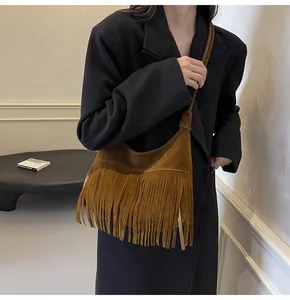 Detail van de karamel suède crossbodytas met dichte franjes en een retro halve maanvorm