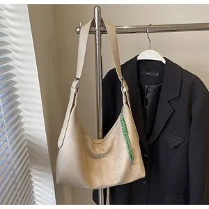 Détail du sac hobo beige avec bandoulière réglable et breloque tissée verte sur cintre