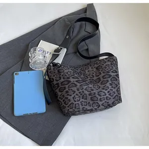 Détail d'un sac cabas léopard gris avec bandoulière en cuir noir et boucle argentée