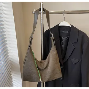 Détail du grand sac cabas en daim vert armée avec bandoulière tissée sur un cintre