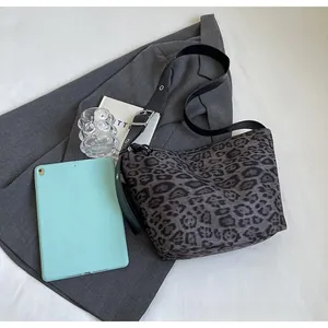 Détail d'un sac léopard gris avec large bandoulière noire et boucle métallique