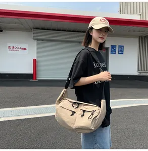 Outdoor shot of a beige large nylon crescent bag featuring functional drawstring pockets