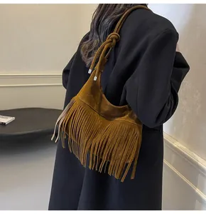 Detail van de suède hobo-tas in karamelkleur met franjes en geknoopte schouderband