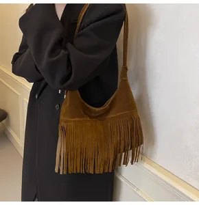 Detail van bruine suède crossbodytas met retro franjes en een gladde lederen textuur
