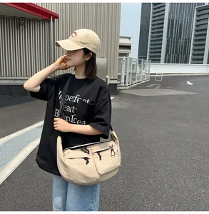 Detail of beige nylon crossbody bag with adjustable strap on a streetwear model