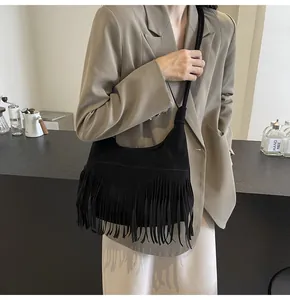 Detail van zwarte suède tas met lange franjes gecombineerd met een kaki blazer
