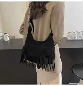 Detail van zwarte suède hobo tas met lange franjes en een brede schouderriem