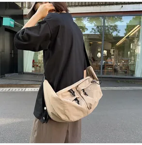 Detail of khaki nylon crossbody bag showing drawstring pockets and wide shoulder strap