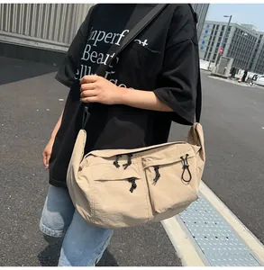 Close-up of beige nylon crossbody bag featuring multi-pocket design and utility straps