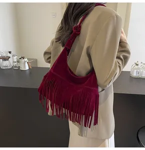 Detail van bordeauxrode suède schoudertas met lange franjes en een geknoopte riem design