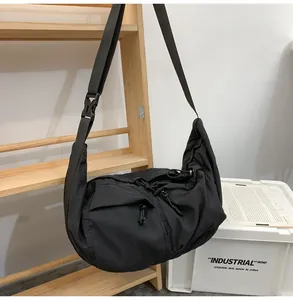 Detail of a black nylon crossbody bag with dual zippered pockets and adjustable strap