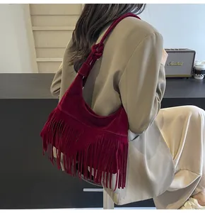 Detail van bordeauxrode suède hobo tas met lange franjes en geknoopte schouderriem