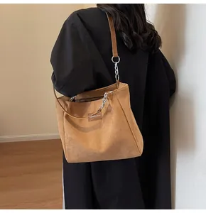 Bolso tote de pana marrón al hombro con cadena plateada y etiqueta de moda