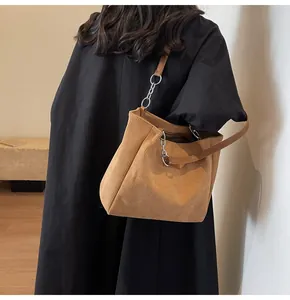Detalle del bolso tote de pana marrón con cadena plateada y correa de cuero y retales