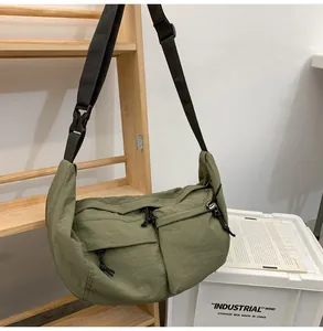Detail of olive green nylon crossbody bag showing dual zip pockets and adjustable strap
