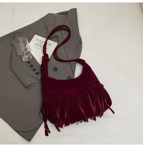 Detail van bordeauxrode suède crossbodytas met bohemien franjes en matte textuur