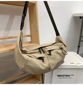 Detail of khaki nylon crossbody bag showing utility pockets and adjustable black strap
