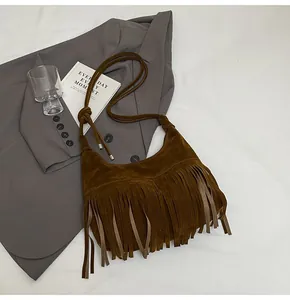 Detailopname van de donkerbruine suède halve maan tas met lange decoratieve franje kwastjes