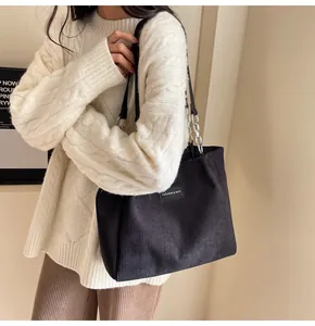 Detalle del bolso tote de pana negra con etiqueta de moda y cadena de metal plateado