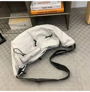 Detailed view of light gray nylon crossbody bag with drawstring and adjustable strap