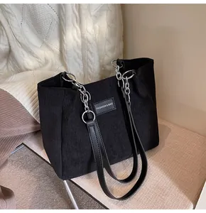 Detalle del bolso tote de pana negra con rayas verticales y correa de cadena metálica