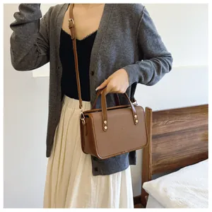 Gros plan du sac bandoulière marron texturé avec poignée en cuir et clous métalliques