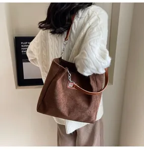Primer plano del bolso tote de pana marrón con etiqueta de moda y correa de cadena metálica