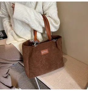 Detalle del bolso tote de pana marrón con asas de cuero y parche de moda lateral