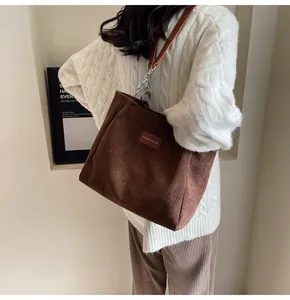 Detalle del bolso tote de pana marrón con correa de cadena y etiqueta de moda en cuero