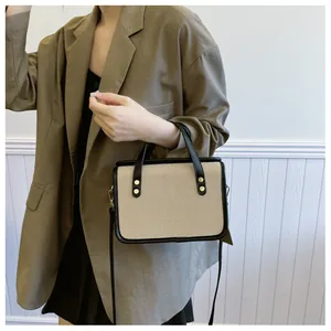 Détail du sac en toile beige avec garniture en cuir noir et rivets dorés brillants