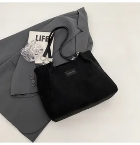 Detalle del bolso tote de pana negra con textura de rayas y correa de cadena metal