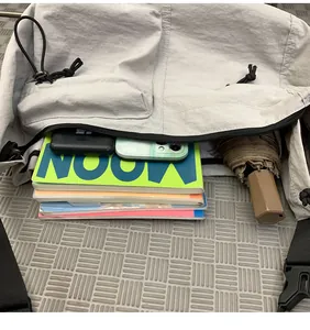 Top-down view of a spacious light gray nylon crossbody bag with items inside